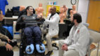 Medical students examine a patient in a wheelchair