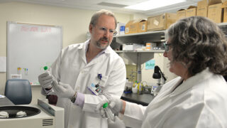 Two scientists hold test tubes in a lab