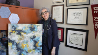 Doctor stands in front of her artwork