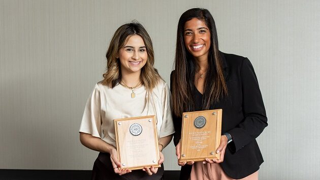 Two women holding wooden award plaques.